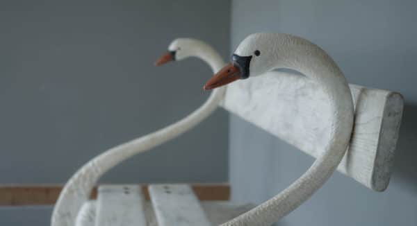 an elegant cast iron and wood garden bench in the design of a swan