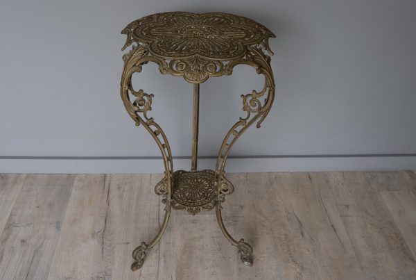 Tall antique iron plant stand, Art Nouveau in style, featuring an upper and smaller lower tier shelf. Intricate iron detail throughout, this decorative plant stand or jardiniere sits on three sturdy legs. This antique table retains its original finish.