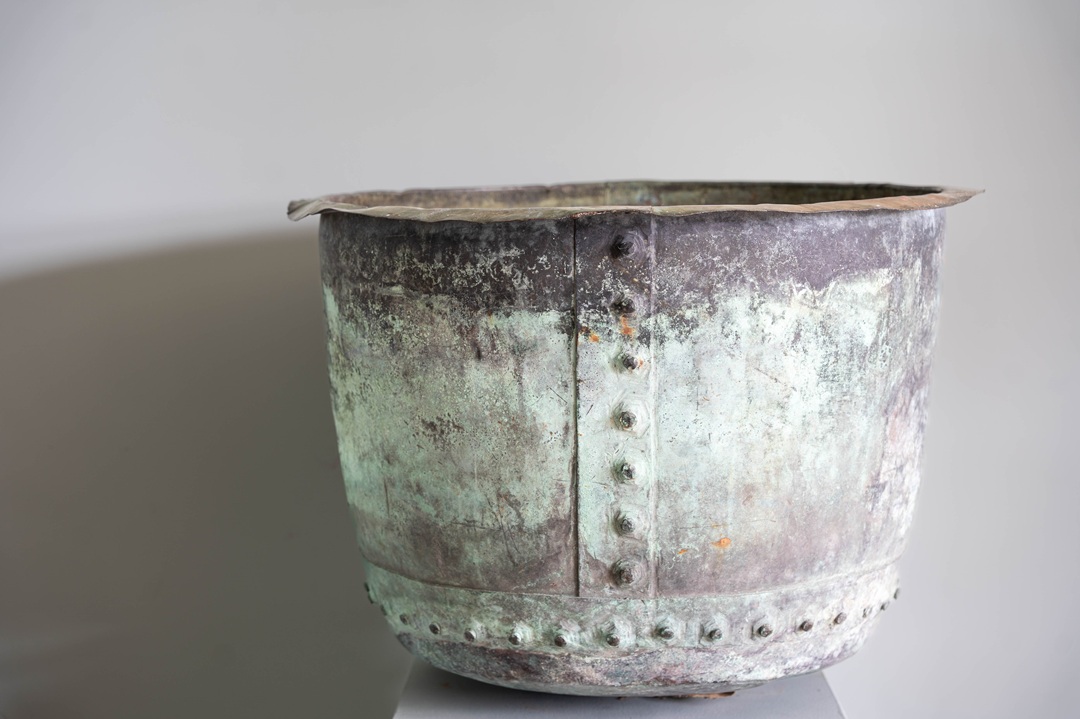 an antique riveted copper pot planter