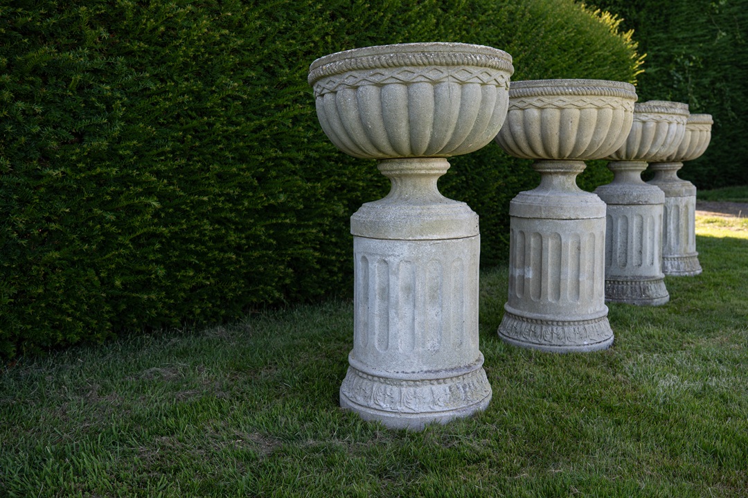 a set of four garden urns on plinths