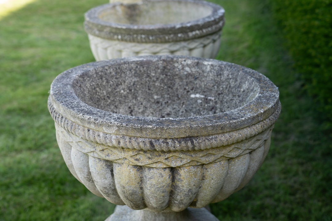 a set of four vintage garden urns on plinths