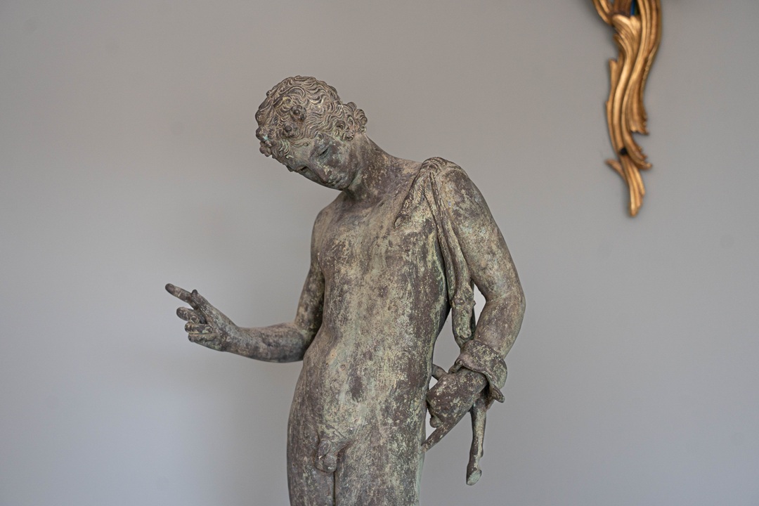 an antique bronze statue of Narcissus
